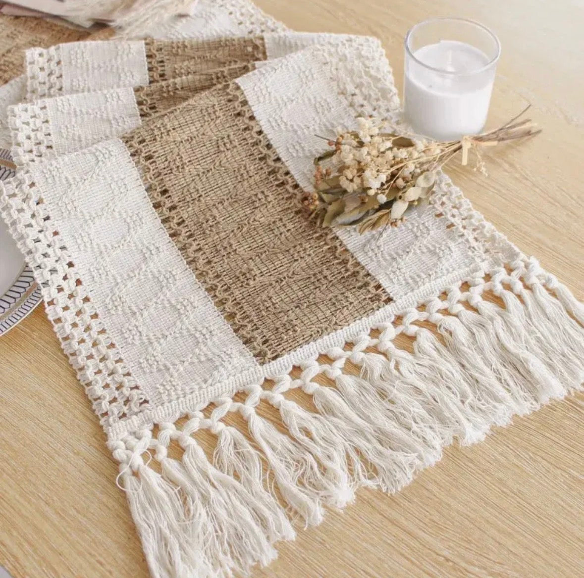 Crocheted table runner with burlap and tassel details on a wooden surface.