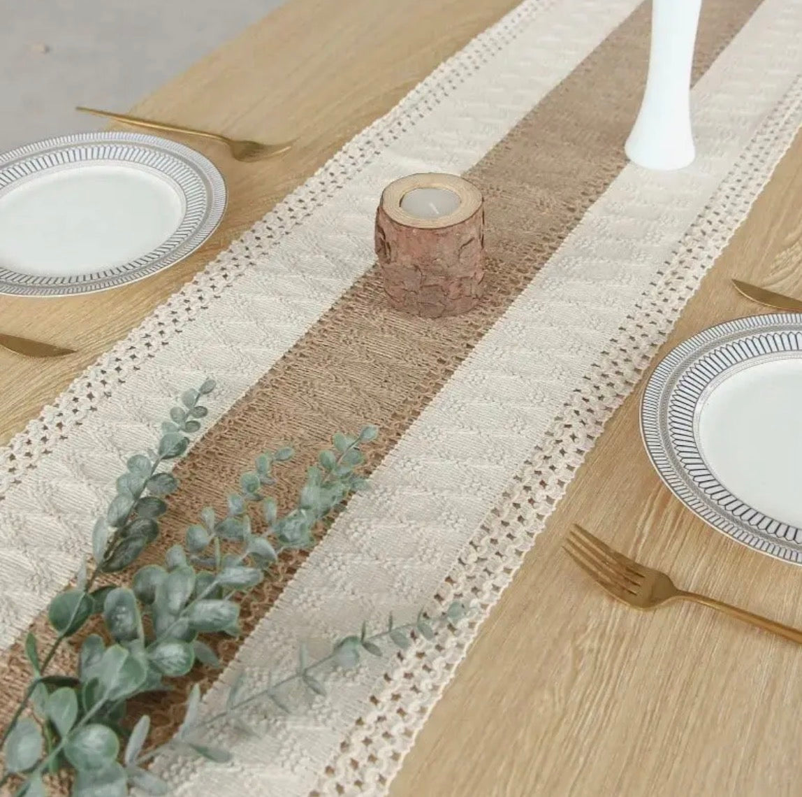 Dining table setting with a striped table runner, plates, and cutlery.