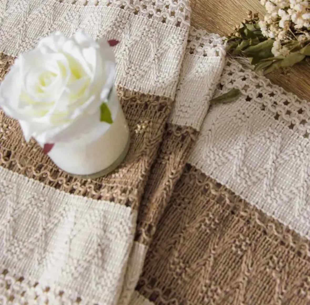 Knitted fabric with a white rose and dried flowers on a textured surface