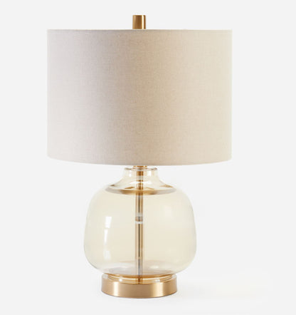 Table lamp with a beige shade and glass base on a white background