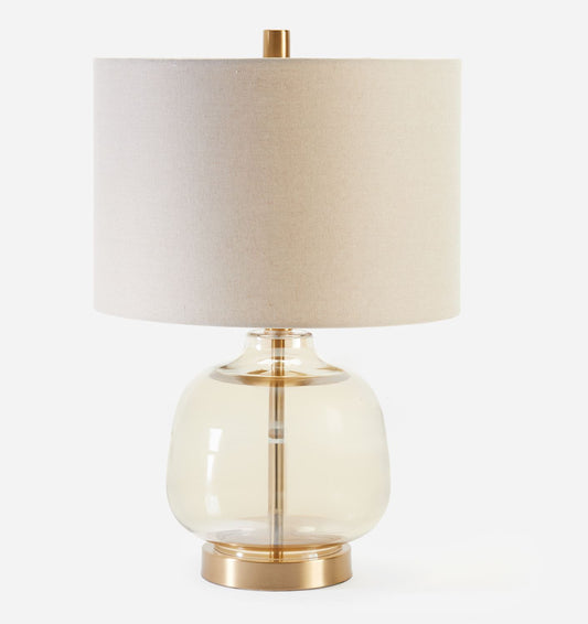 Table lamp with a beige shade and glass base on a white background