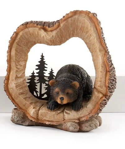 Bear laying down in log figurine 