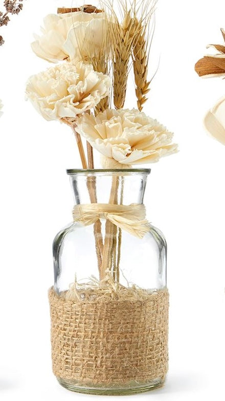 A clear glass jar containing an arrangement of natural dried flowers, tied with a rustic jute ribbon