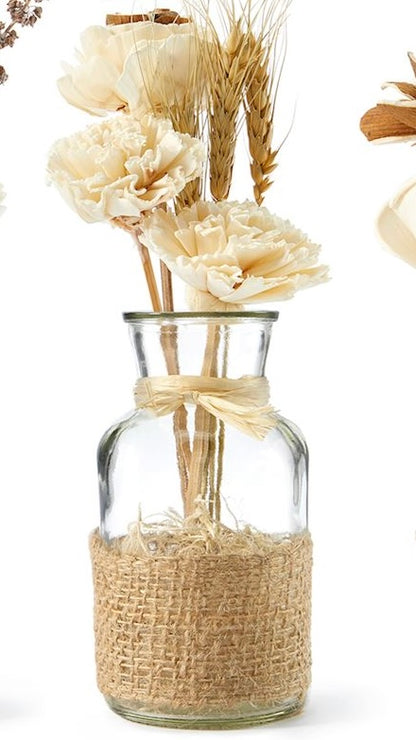 A clear glass jar containing an arrangement of natural dried flowers, tied with a rustic jute ribbon