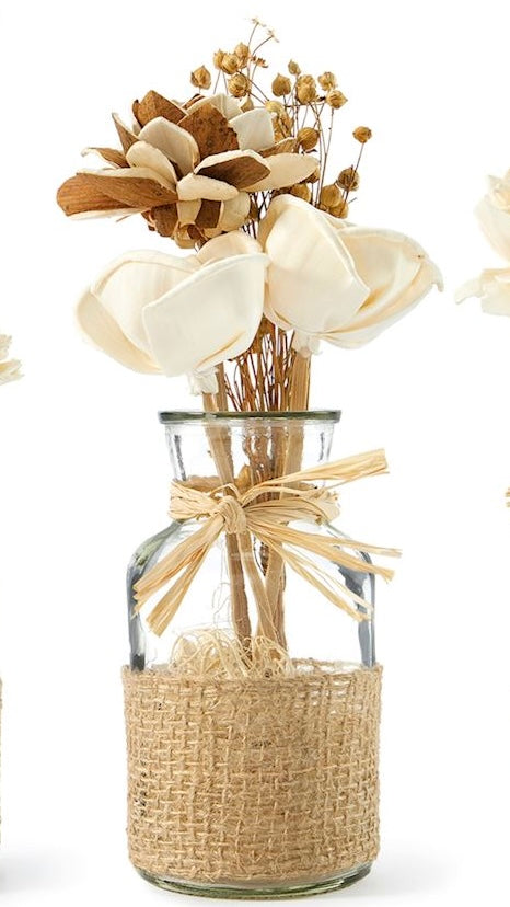 A clear glass jar containing an arrangement of natural dried flowers, tied with a rustic jute ribbon