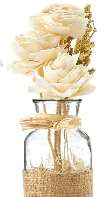 A clear glass jar containing an arrangement of natural dried flowers, tied with a rustic jute ribbon